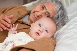 Great Grandma and great granddaughter snuggling on white sheet